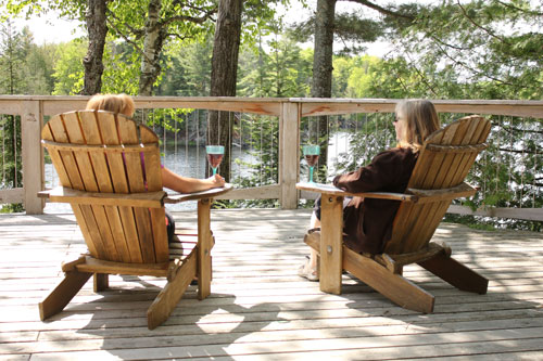 Two women sitting on the wooden deck with glass of drink