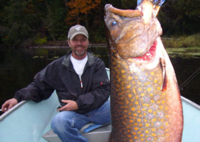 A man sitting in the boat and posing with the large fish