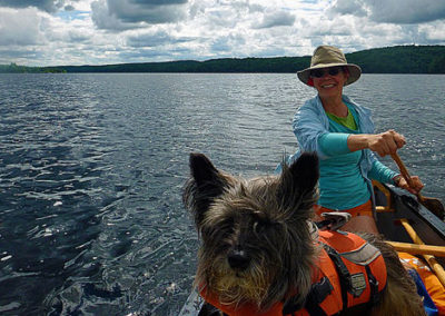 A woman and her pet dog canoeing in the river